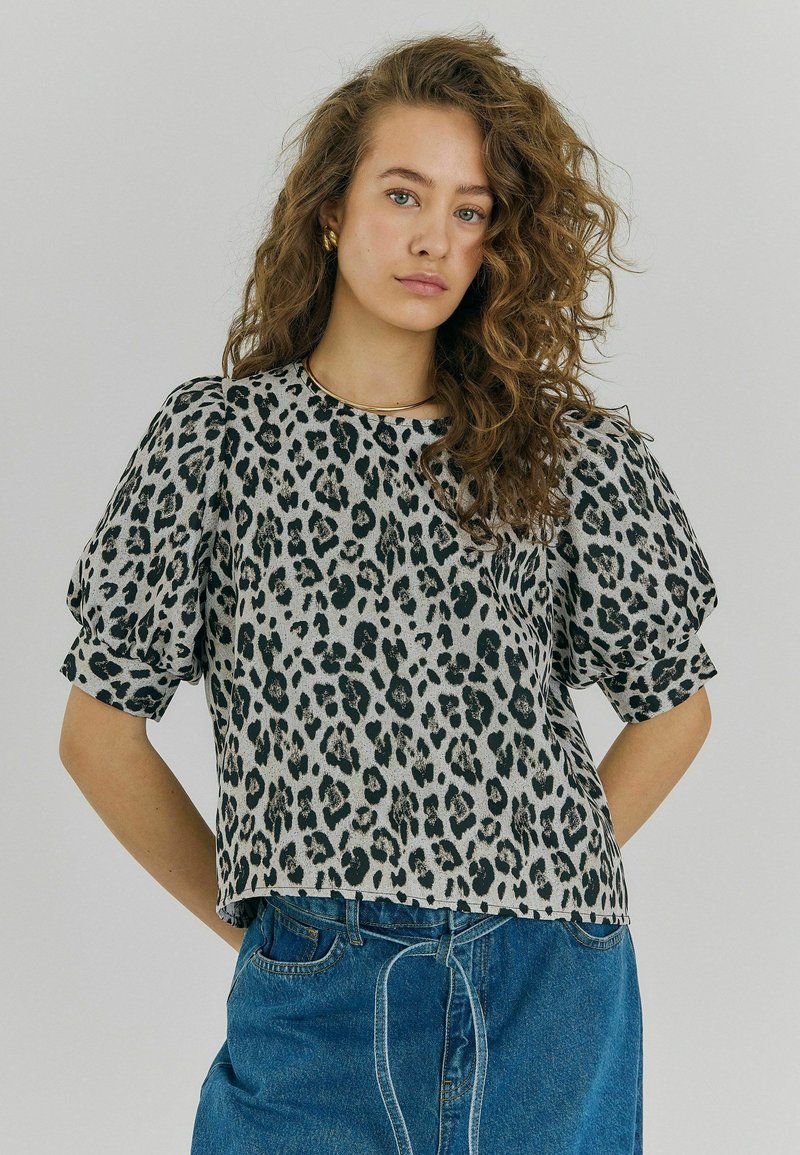 Leopardmönstrad blus med korta, puffiga ärmar, rund halsringning och en lös passform. Tillverkad av lätt tyg med en subtil lyster.