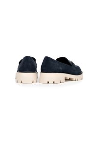 Mocasines de ante azul marino con una suela de goma beige gruesa y costuras detalladas en la parte trasera. Presentan una punta redondeada y un tacón plano.