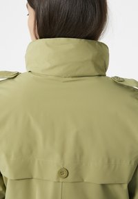 Jasnozielona wodoodporna kurtka z wysokim kołnierzem, detalami guzików i gładką teksturą; posiada naramienniki i elegancki design.