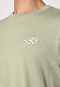 Lichtgroene Puma T-shirt, korte mouwen, ronde hals, zachte stof, met geborduurd logo in off-white op de linkerkant van de borst.