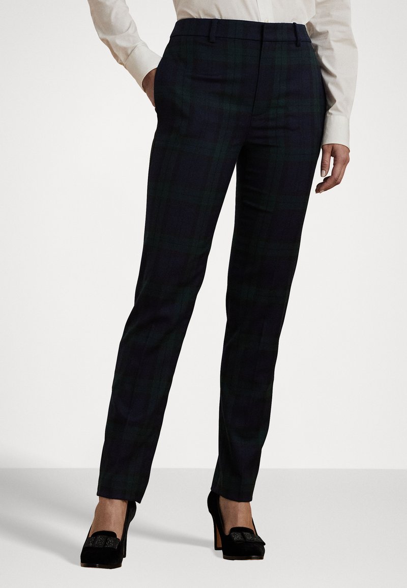 Pantalones a cuadros en verde oscuro y azul marino, fabricados con tejido tejido, de corte ajustado y textura suave. Combinados con zapatos de tacón alto negros.