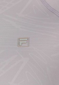Top de tirantes de lavanda claro con una sutil textura acanalada, que presenta un pequeño logo encerrado en el centro. Bordes cosidos sin embellishments adicionales.