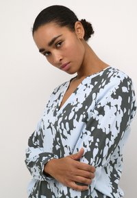 Geprinte blouse met een lichtblauwe basis en donkergrijze abstracte patronen, V-hals, lange mouwen en een zachte, gladde stofstructuur.