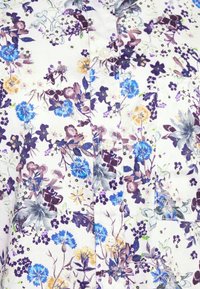 Hvidt stof med et blomstermønster indeholdende blå, lilla og gule blomster; inkluderer knapper og en lomme detalje.