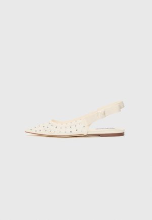 Pointed toe slingback shoe in cream with metallic studs, fabric upper, elastic strap, and a flat sole. Smooth texture and minimal design.