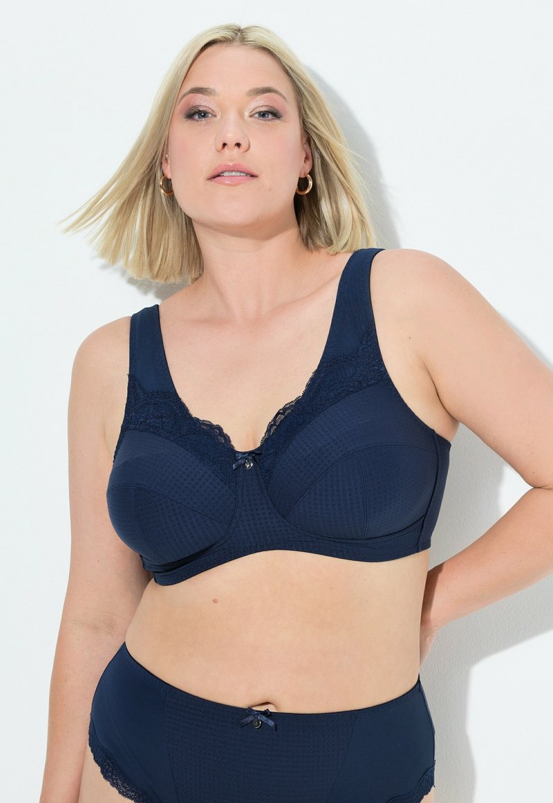 Navy blauwe bh en bijpassende hoge slip met textuurstof, kantafwerking en strikaccenten in het midden en op de tailleband.