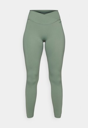 High-waisted leggings in muted green fabric, featuring a seamless design, smooth texture, and subtle cross-over waistband detailing.
