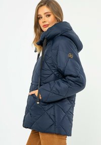 Námorně modrá péřová bunda s kapucí, prošívaný diamantový vzor, nastavitelná šňůrka, boční kapsy a nášivka s logem na rukávu.