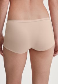 Beige boyshort ondergoed gemaakt van rekbaar materiaal. Kenmerkt zich door een naadloos ontwerp met een gladde tailleband en geen zichtbare stikdetails.