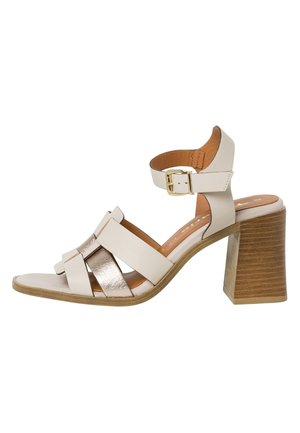 Licht beige blokhak sandalen met metallic accenten, voorzien van gekruiste banden en een verstelbare enkelband met een gouden gesp.