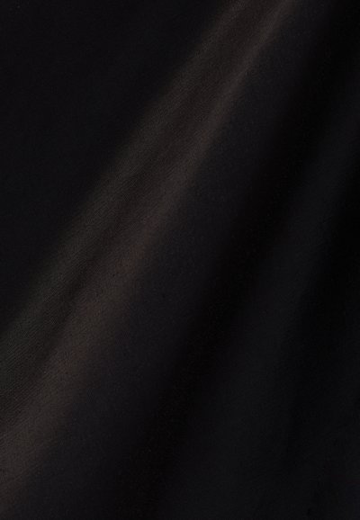 Λείο μαύρο ύφασμα με απαλές πτυχές και διακριτικές αντανακλάσεις φωτός που αναδεικνύουν την υφή και τη λάμψη του.