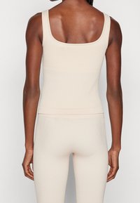 Top de tirantes acanalado en beige claro con escote cuadrado y tirantes anchos, con una silueta ajustada y dobladillo sin costuras.