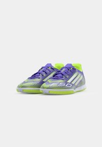 Paarse en groene voetbalschoenen met een textuurontwerp, met een opvallend "F50" logo en drie witte strepen aan de zijkanten.