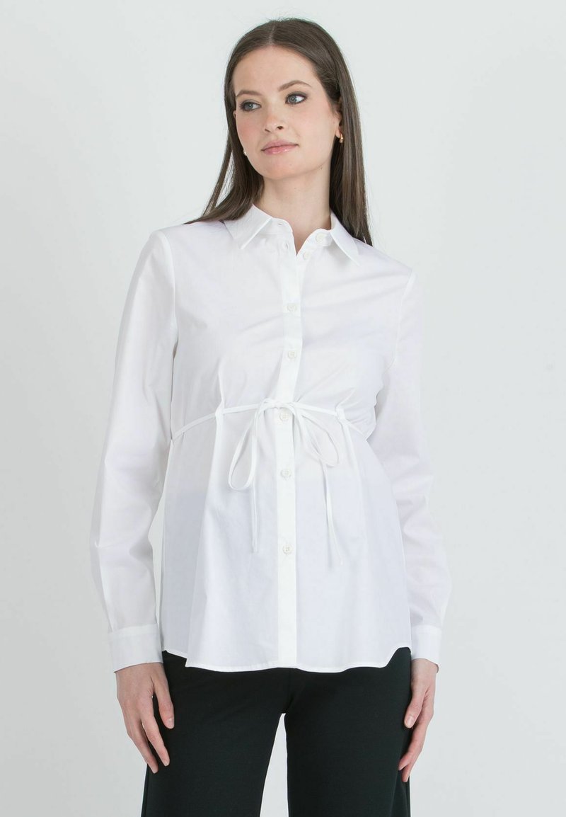 Weißes Hemd mit Kragen, langen Ärmeln und Kordelzug in der Taille. Der Stoff ist glatt und knitterfrei und sorgt für einen strukturierten Look.