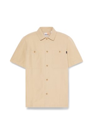Camicia beige a maniche corte con bottoni, due tasche sul petto e colletto, etichetta Timberland all'interno del colletto e piccola etichetta nera sul lato.