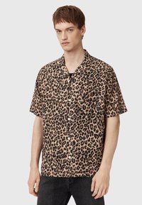 Kortærmet skjorte i beige med sort leopardprint, med knaplukning foran og en enkelt brystlomme. Teksturstof.