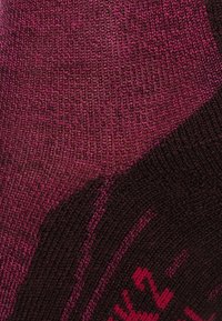 Calcetines de punto en tonos burdeos oscuros y rosas, con un patrón texturizado y superficie lisa, que presentan acentos de diseño en contraste.