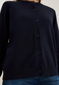 Marineblauwe cardigan met een ronde hals, vijf zwarte knopen aan de voorkant, geribbelde zoom en een gladde breistekstuur.