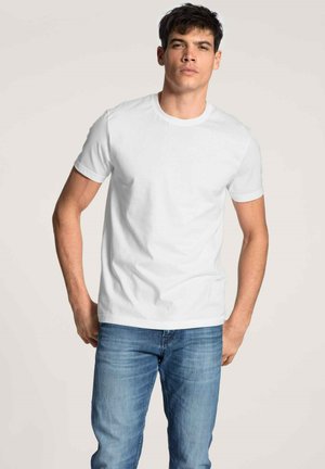 Weißes Baumwoll-T-Shirt mit rundem Halsausschnitt und kurzen Ärmeln, kombiniert mit blauen Jeans. Glatte Textur und klassischer Schnitt.