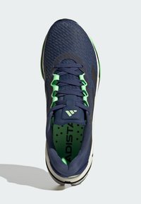 Navy running shoe with textured upper, green accents, black logo, padded tongue, and perforated insole. Features a durable outsole.