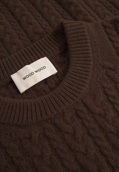 Rjav pleten pulover z vzorcem kabla, rebrastim ovratnikom in oznako z napisom "WOOD WOOD." Mehka tekstura in srednja debelina.