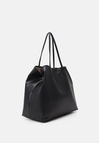Geantă tote din piele neagră cu o suprafață texturată, două mânere lungi și o formă relaxată. Remarcabilă pentru designul său minimal și lipsa accesoriilor.