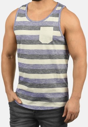 Homme portant un débardeur sans manches à rayures horizontales grises, blanches et violettes avec une petite poche blanche sur la poitrine, associé à un jean foncé.