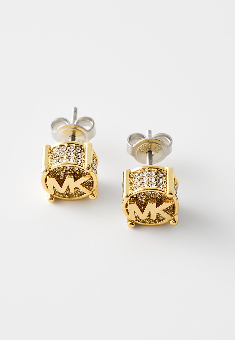 Boucles d'oreilles à clou en ton or avec des embellissements en cristal, présentant un design circulaire et les lettres gravées "MK". Fermoir à tige en ton argent.