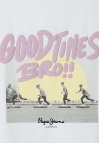 Bílá tričko s grafickým potiskem čtyř skateboardistů v černobílé, s růžovým textem "DOBRÉ ČASY BRA!!" a žlutým kruhem.