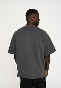 Overdimensioneret grå bomulds t-shirt med rund hals, korte ærmer og en afslappet pasform. Glat tekstur med syede kanter.