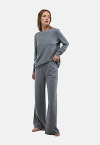 Ensemble de détente gris composé d'un haut à manches longues avec un col rond et d'un pantalon évasé, fabriqué à partir d'un tissu doux et texturé.
