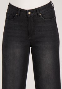 Zwarte spijkerbroek met een rechte pijp, voorzien van een voorzak, een metalen knoop en subtiele stiksel-details.