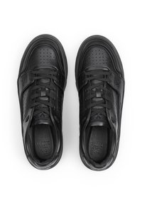 Un paio di sneaker in pelle nera con lacci, zona delle dita perforata e colletto imbottito, mostrato dall'alto su uno sfondo bianco.