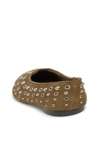 Zapato de ante marrón con ojales de plata redondos, parte trasera baja y textura suave. Punta redondeada y suela de goma plana diseñada para mayor comodidad.