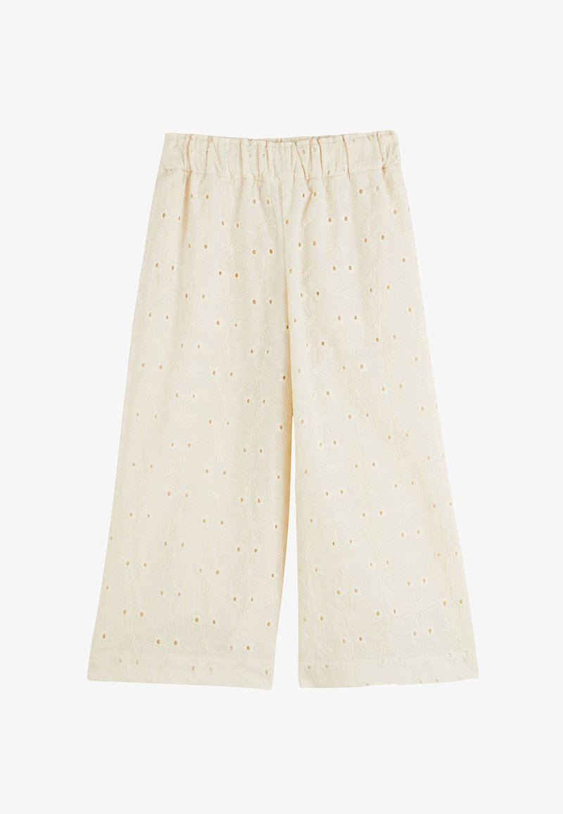Culottes en coton beige clair avec une taille élastique, présentant des motifs floraux et de petits trous en œillet dans tout le tissu.