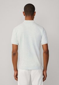 Světle šedé polo tričko s krátkými rukávy, s klasickým límečkem a strukturovanou, melírovanou tkaninou. Bez viditelných log a vzorů.