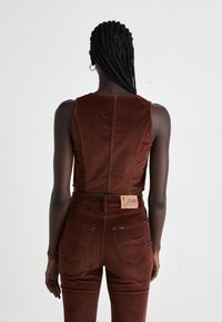 Bruine corduroy crop top met een ronde halslijn, gecombineerd met hoge bruine corduroy broeken. Lee logo patch op de tailleband.
