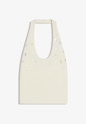 Haut sans manches en tissu crème avec encolure large et petites décorations en perles dispersées sur le devant.