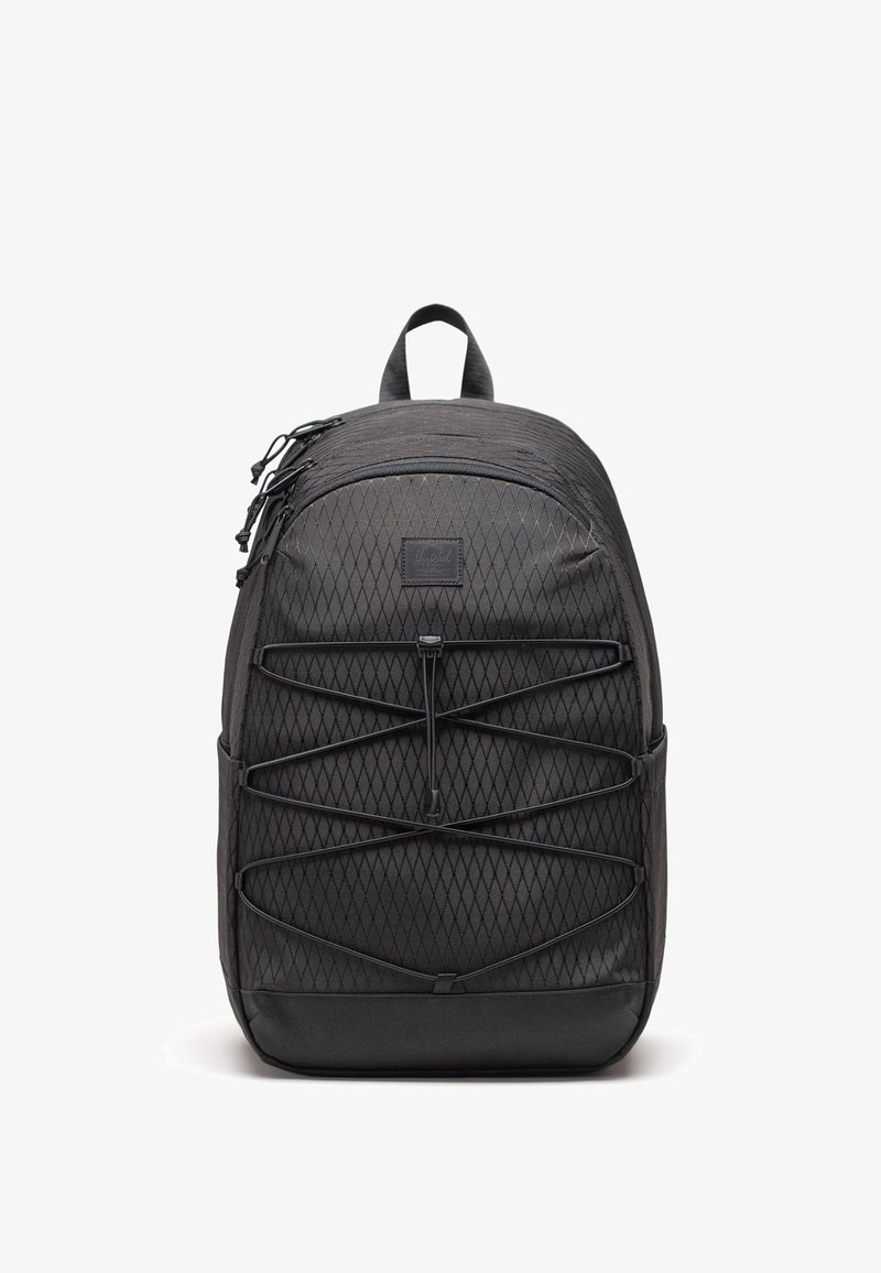 Sac à dos noir avec tissu à motif losange, cordons élastiques devant, poignée supérieure et plusieurs compartiments zippés, présenté sur fond blanc.
