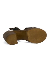 Brauner Holzplattform-Schuh mit strukturiertem Boden, ausgestattet mit einem klobigen Absatz und einem schwarzen Riemen über dem Fuß.