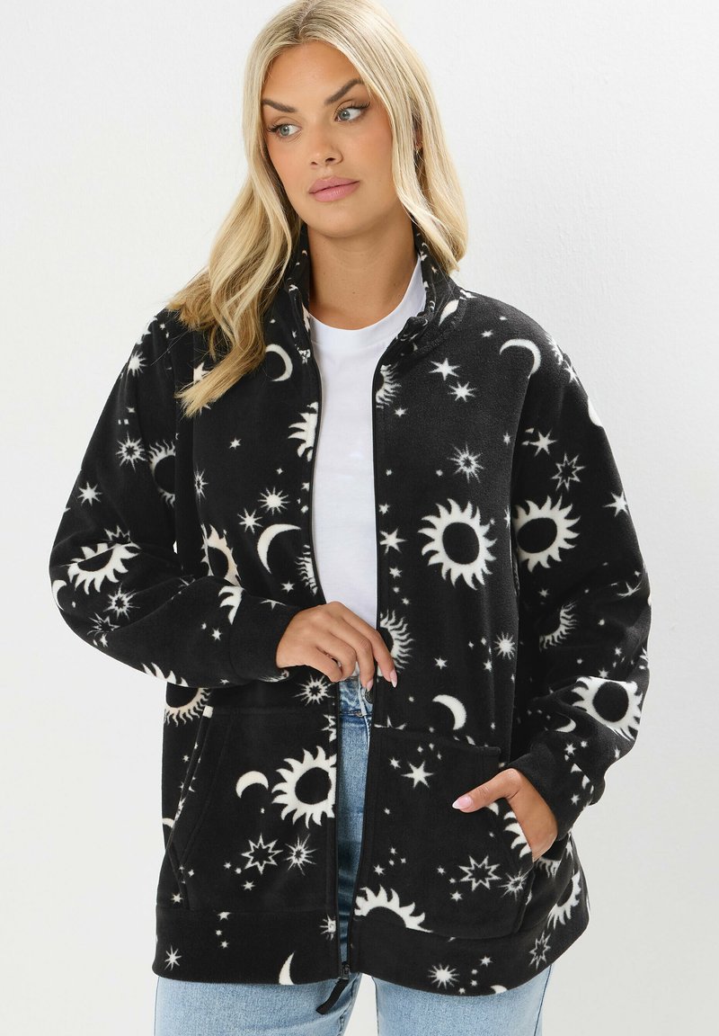 Mustat fleece-takit, joissa on valkoisia taivaankappaleita; siinä on vetoketjukiinnitys, kaksi taskua, pitkät hihat ja pehmeä, tekstuuriainen kangas.