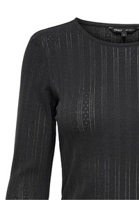 Schwarzes Langarmshirt mit rundem Halsausschnitt, das über ein strukturiertes, geripptes Muster und kleine Perforationen verfügt, aus einem dehnbaren Stoff gefertigt.