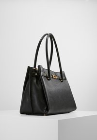 Borsa a mano in pelle nera con finitura testurizzata, hardware in tonalità oro, due manici curvi e forma strutturata. Chiusura regolabile con dettagli decorativi.