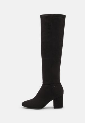 Bottes noires montantes en suède doux, avec un bout pointu et un talon épais. Design sans couture avec des accents matériels minimes.