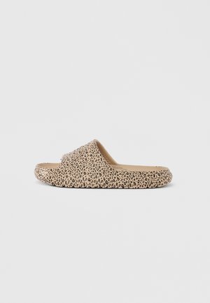 Beige slidesandaal met zwart luipaardprintpatroon en een gestructureerde zool, getoond vanaf de zijkant op een effen lichte achtergrond.