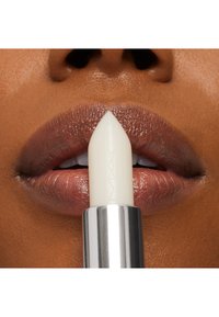 Ein weißer Lippenstiftstift, der auf glänzenden, mitteltonigen Lippen zeigt. Der Stift hat eine elegante silberne Hülle mit dem eingeprägten "MAC"-Logo.