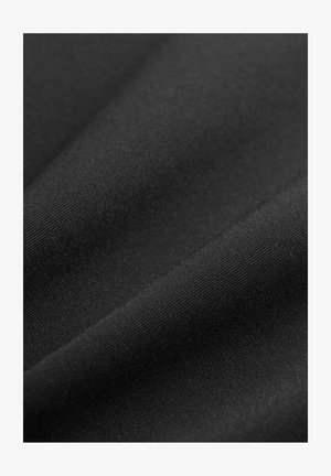 Lähikuva siledast mustast kangast, millel on peen kudumine ja peened voldid, mis loovad pehmeid varjusid ja tekstuuri.