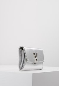 Sölvmetallisk kuvertväska med en texturerad yta, som har en viklock och en distinkt 'V' hårdvaruaccent. Kompakt storlek.