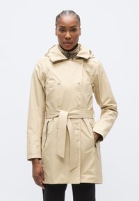 Μπεζ αδιάβροχο παλτό με διπλό πέτο, ρυθμιζόμενη ζώνη και πλαϊνές τσέπες με φερμουάρ. Διαθέτει ευρύχωρη κουκούλα και λεία υφή.