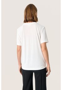 Vit kortärmad t-shirt i mjukt, lätt material. Har en rund halsringning och en avslappnad, loose fit. Bakifrån framhäver den enkelheten.